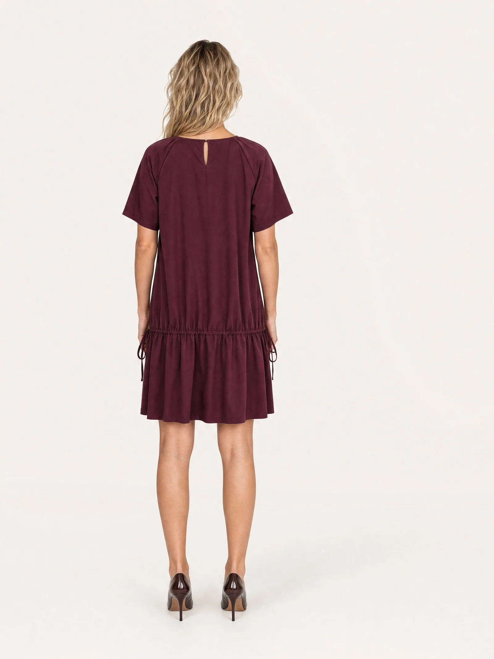 The same model and dress photographed from the back, full length on the same backdrop