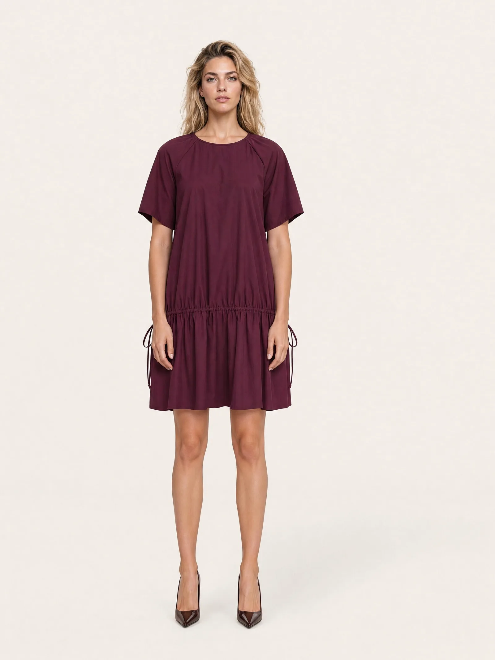 The dress worn by a model on a plain studio backdrop, photographed from the front, full length