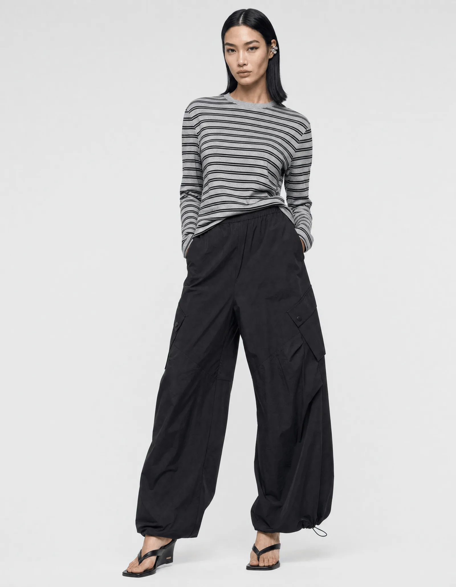 A model wearing the striped longsleeve tucked into the black cargo trousers, shot full length on a plain studio backdrop